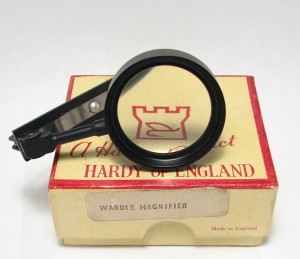 A Second Model “Wardle” Magnifier By Hardy, In It’s Original Box. The First Model Is All Brass With A Two-Piece Frame, While The Second Model Is Painted Black And Has A One-Piece Frame.